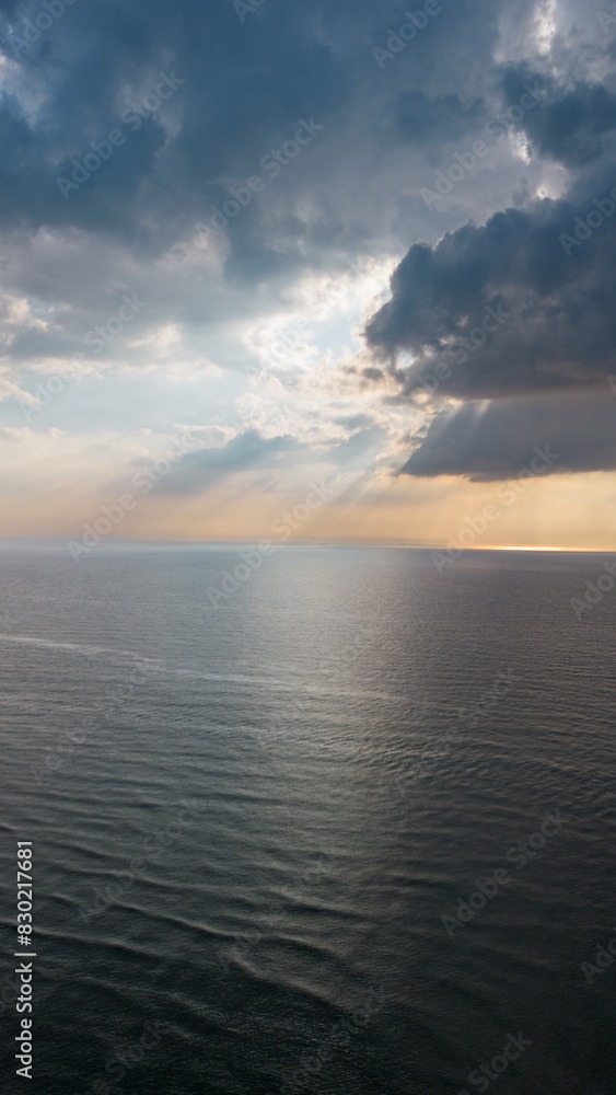 Beautiful sunset over the sea, ocean. Top view from a quadcopter. Beautiful flight. Ships and windmills on the horizon. The rays of the sun break through the clouds. Beautiful sunset over the sea, ocean. Top view from a quadcopter. Beautiful flight. Ships and windmills on the horizon. The rays of the sun break through the clouds.