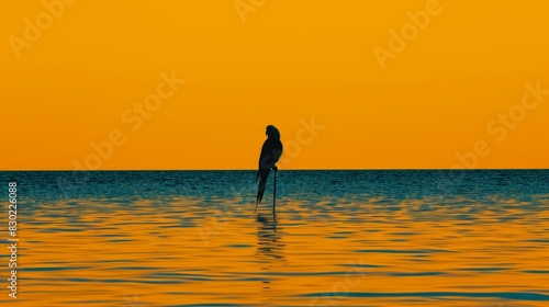  A bird perches atop a pole  surrounded by a body of water Behind  a vibrant yellow sky unfolds In the water s expanse  a solitary bird stands