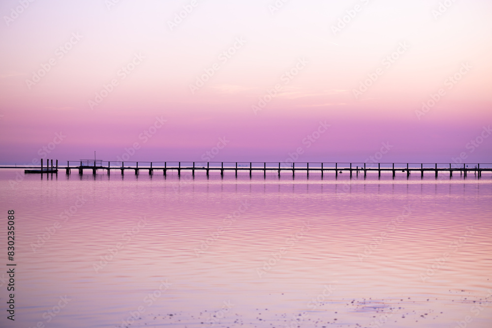 Sunset sea with wooden pier and boat on background
