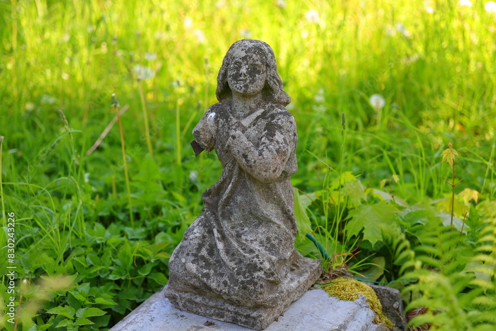 A stone figurine covered with tarnish and a green background A stone figurine covered with tarnish and a green background