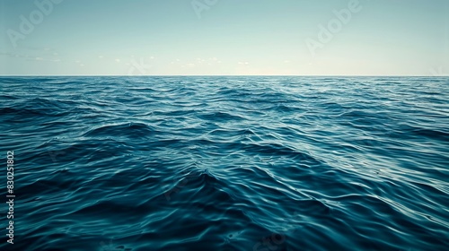  A expansive body of blue water is framed by a clear sky, bearing scattered larger clouds near the horizon and smaller ones dispersed above photo