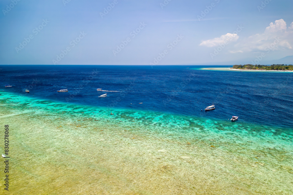 Aerial view of a fringing coral reef and snorkel boats on Gili Trawangan, Indonesia