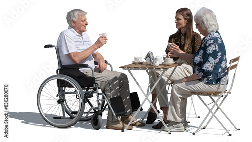 Old man in a wheelchair sitting in an outdoor café with his family isolated on white background photo