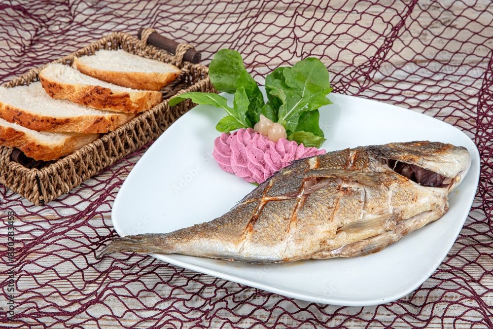 Grilled gilthead sea bream on plate with lemon ,salad and grilled vegetables. Fried sea bream on plate with a lemon. Healthy food. Grilled gilthead sea bream on plate with lemon ,salad and grilled vegetables. Fried sea bream on plate with a lemon. Healthy food.