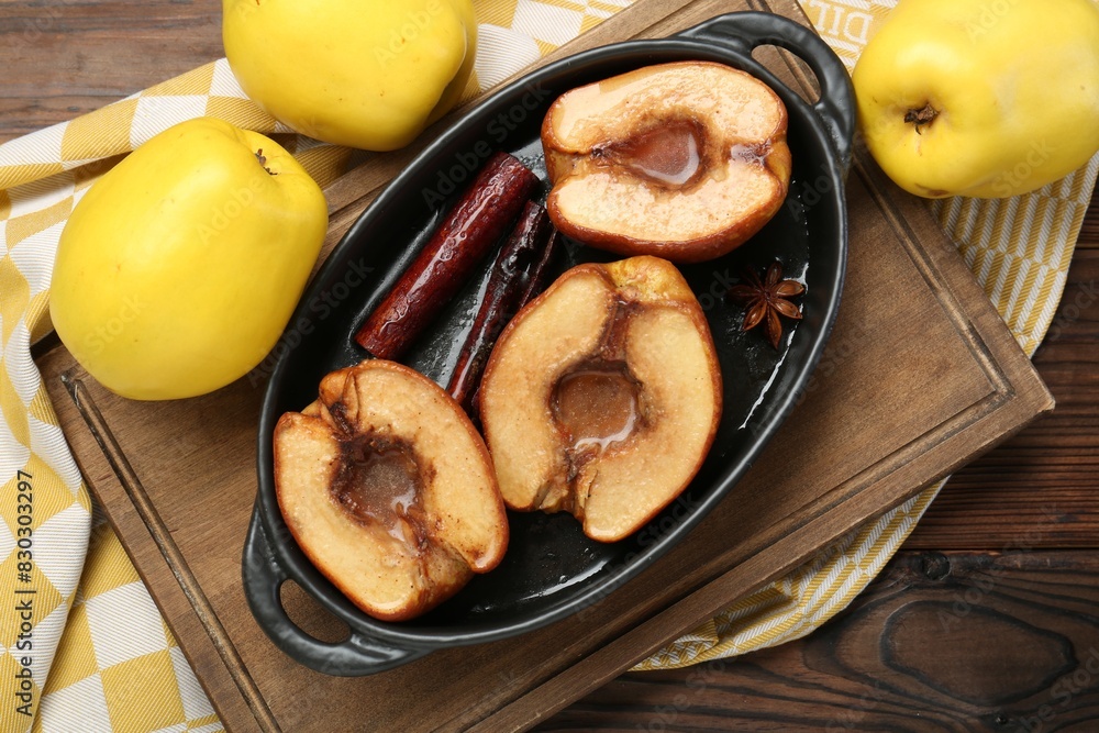Tasty baked quinces with spices and honey in dish on wooden table, flat lay Tasty baked quinces with spices and honey in dish on wooden table, flat lay