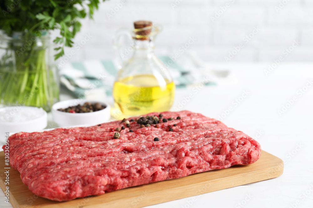 Raw ground meat, spices, oil and parsley on white table Raw ground meat, spices, oil and parsley on white table