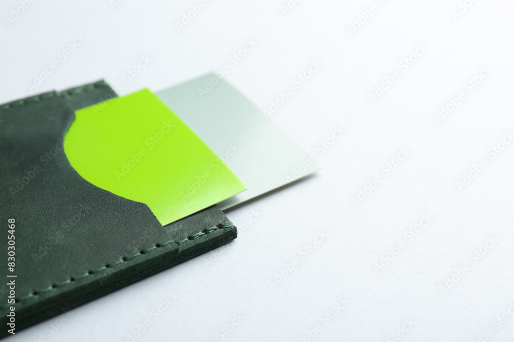 Leather business card holder with colorful cards on light grey background, closeup. Space for text Leather business card holder with colorful cards on light grey background, closeup. Space for text