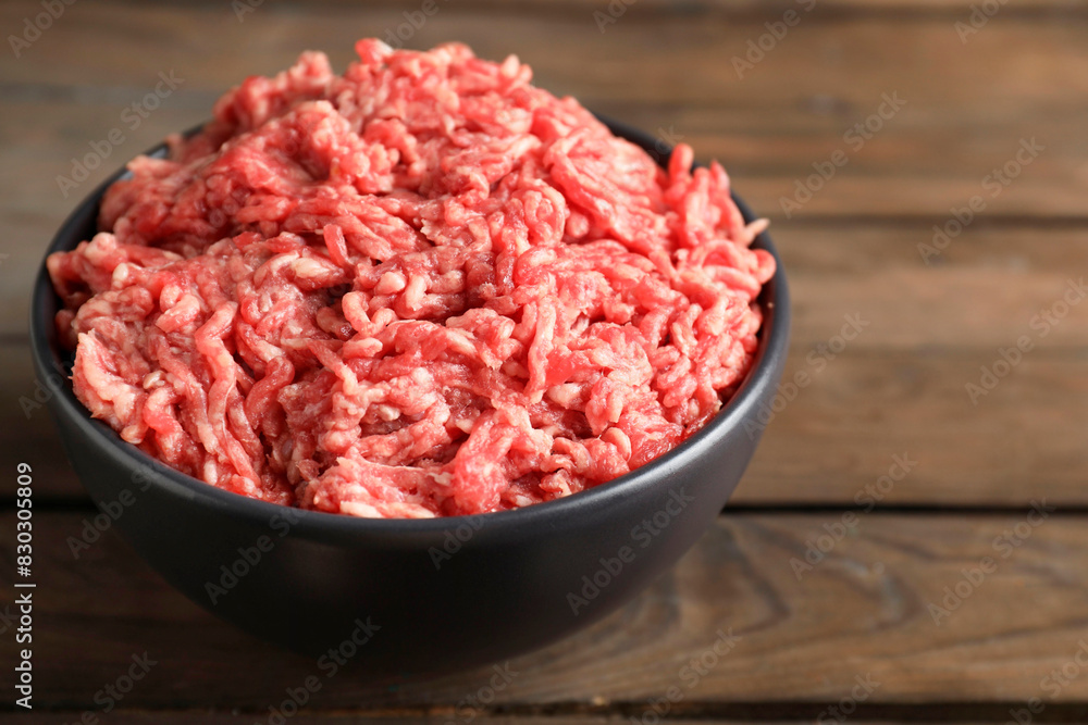 Raw ground meat in bowl on wooden table, closeup Raw ground meat in bowl on wooden table, closeup