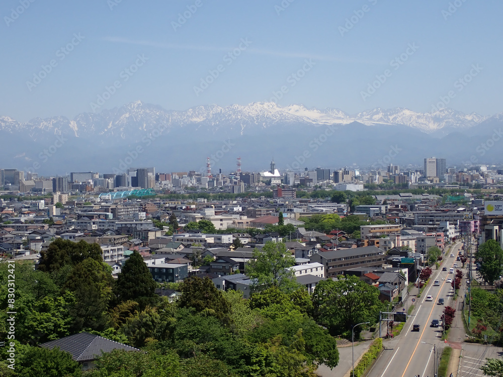 Obraz premium 5月新緑の呉羽山富山県道44号富山高岡線を跨ぐ遊歩道吊橋から北アルプス剱岳立山連峰富山市街地を望む