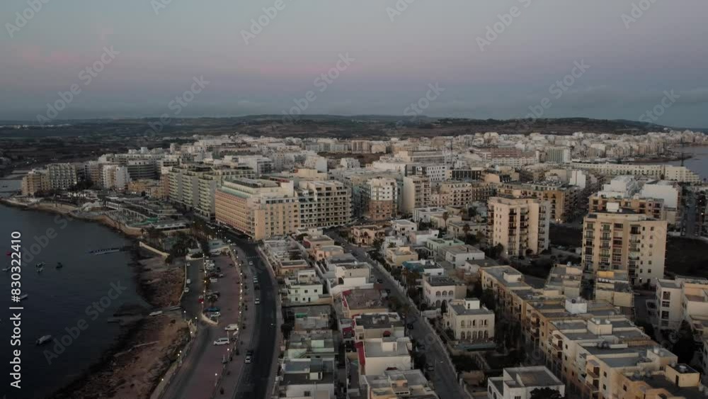 Qawra cityscape in the early morning, during the sunrise. Revealing empty coastal road in golden hour. Aerial. High quality 4k footage Qawra cityscape in the early morning, during the sunrise. Revealing empty coastal road in golden hour. Aerial. High quality 4k footage