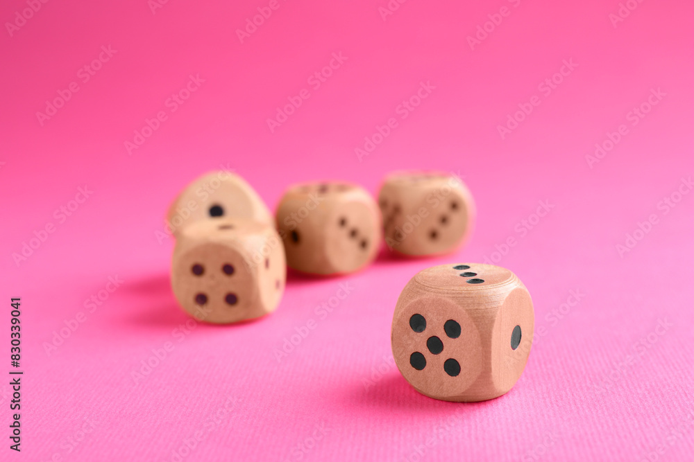 Many wooden game dices on pink background, closeup Many wooden game dices on pink background, closeup