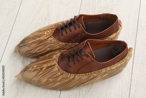 Men`s shoes in shoe covers on light wooden floor photo