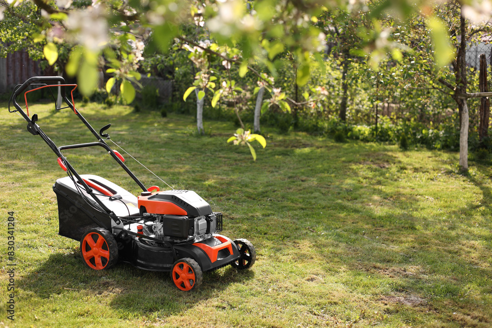 Modern lawn mower on green grass in garden Modern lawn mower on green grass in garden