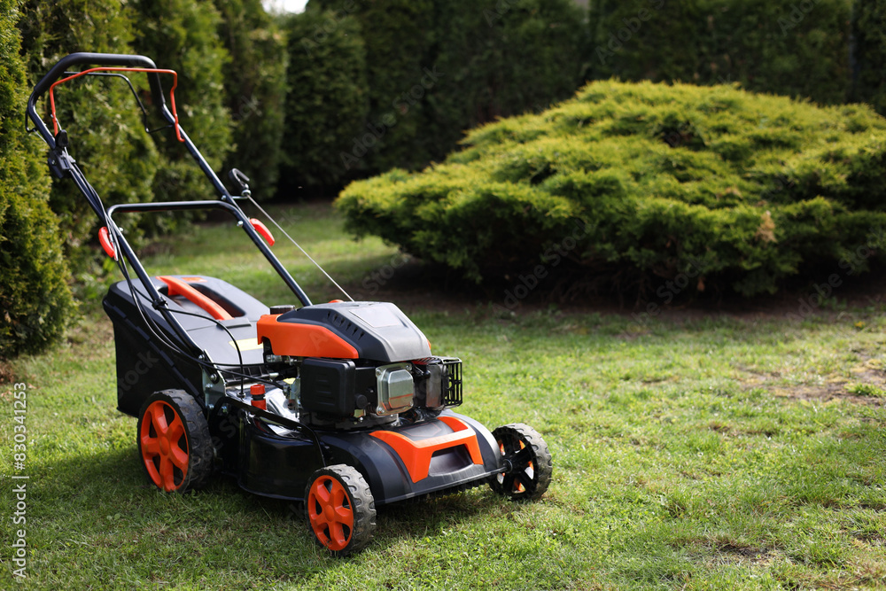Modern lawn mower on green grass in garden Modern lawn mower on green grass in garden