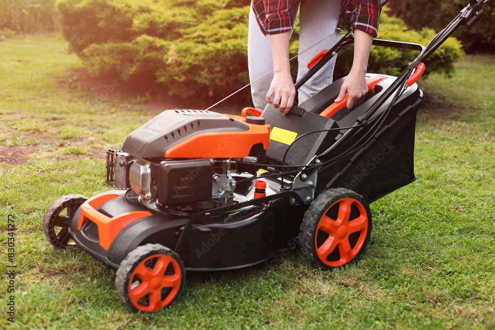 Fototapeta premium Woman with modern lawn mower in garden, closeup