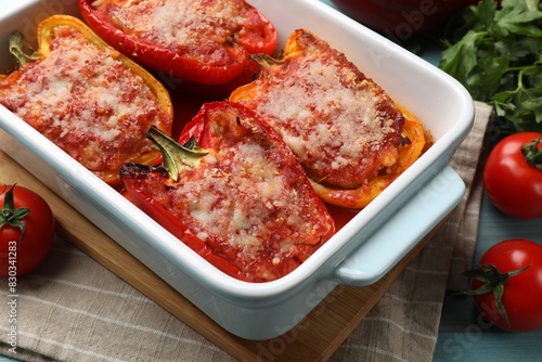 Tasty stuffed peppers in dish and ingredients on light blue wooden table, closeup