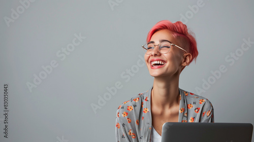 Inclusive image of a happy lesbian employee on laptop. Smiling gay female businesswoman with pink hair working on laptop. Plain grey background. Copy space for text photo