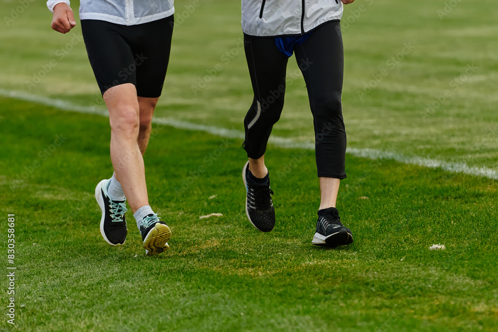An inspiring and active elderly couple showcase their dedication to fitness as they running together on a lush green field, captured in a close-up shot of their legs in motion. An inspiring and active elderly couple showcase their dedication to fitness as they running together on a lush green field, captured in a close-up shot of their legs in motion.