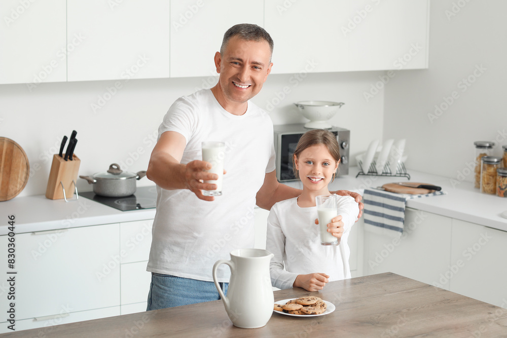 Little girl and her father with cookies drinking milk at table in kitchen Little girl and her father with cookies drinking milk at table in kitchen