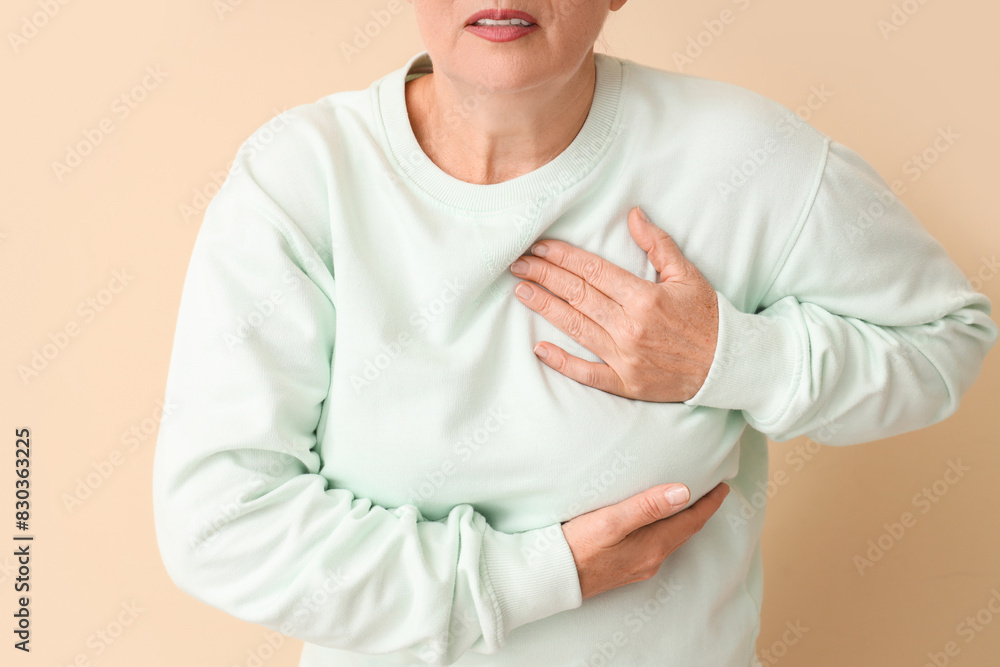 Mature woman suffering from breast pain on beige background, closeup. Cancer awareness concept Mature woman suffering from breast pain on beige background, closeup. Cancer awareness concept