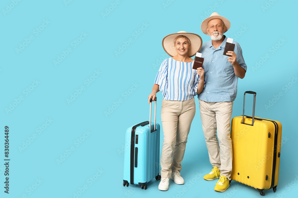 Mature couple with passports and suitcases on blue background. Travel concept Mature couple with passports and suitcases on blue background. Travel concept