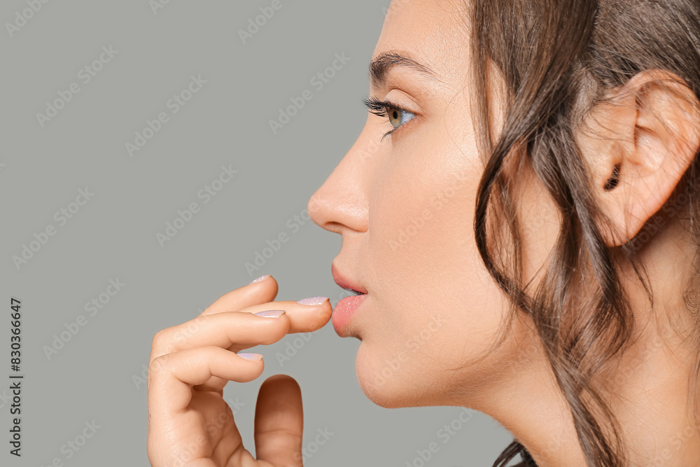 Beautiful young woman applying lip balm against grey background, closeup Beautiful young woman applying lip balm against grey background, closeup