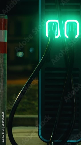 An electric car charging station is highlighted with glowing green lights during the night photo