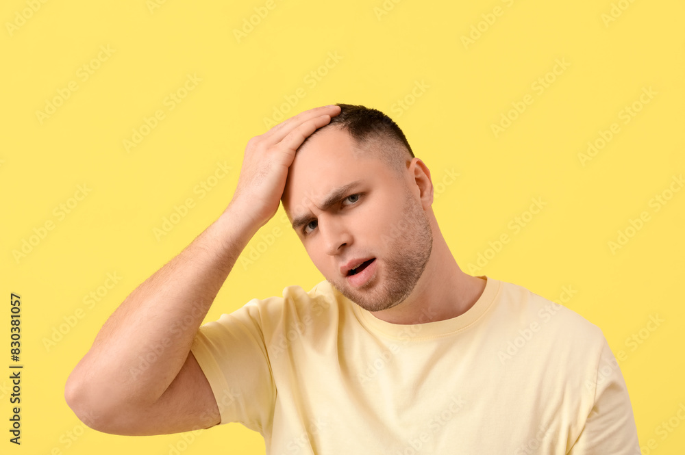 Worried young man with hair loss problem on yellow background, closeup Worried young man with hair loss problem on yellow background, closeup