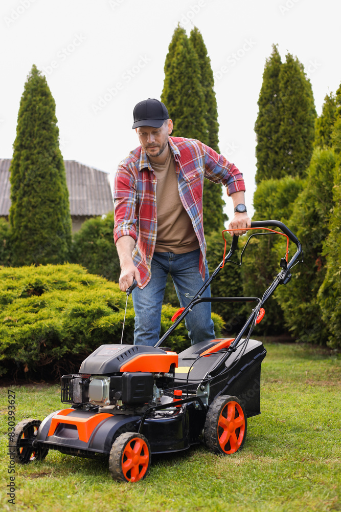 Fototapeta premium Man with modern lawn mower in garden