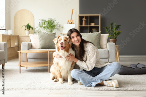 Young woman with Australian Shepherd dog sitting on floor at home