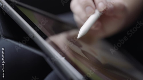 A graphic artist drawing a woman's portrait on a tablet. Close up, slow motion.  photo
