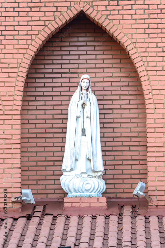 Statue of the image of Our Lady of Fátima, mother of God in the Catholic religion, Our Lady of the Rosary of Fátima, Virgin Mary with the background of a brick wall in Brazil Statue of the image of Our Lady of Fátima, mother of God in the Catholic religion, Our Lady of the Rosary of Fátima, Virgin Mary with the background of a brick wall in Brazil