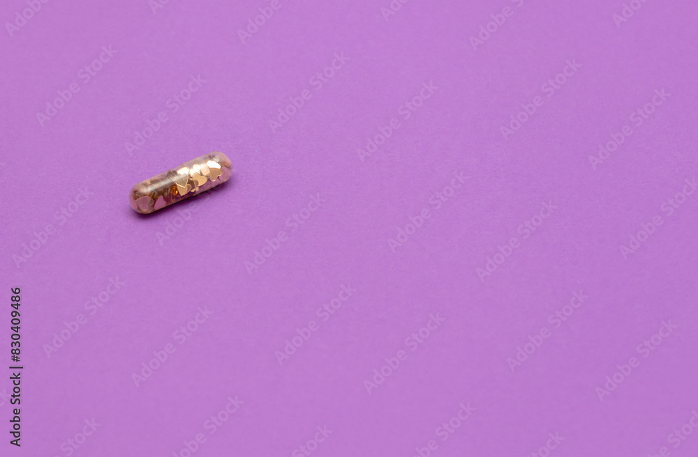 Medical pill capsule filled with golden heart confetti on lavender background. Healing after breakup. Selective focus, copy space Medical pill capsule filled with golden heart confetti on lavender background. Healing after breakup. Selective focus, copy space