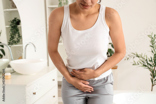 Foto Young woman suffering from menstrual cramps in bathroom, closeup