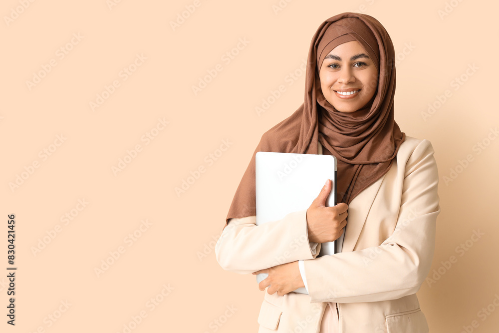 Muslim businesswoman with laptop on beige background Muslim businesswoman with laptop on beige background