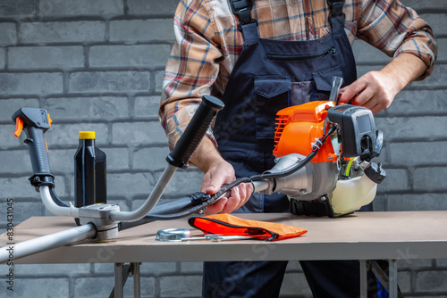 Man, technician repair of petrol mower on work bench. © Sergey