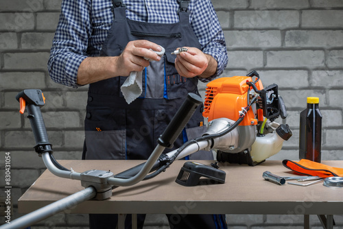 Man, repairman repairing, support petrol strimmer at workshop.