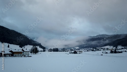 Timelapse of Winter wonderland snow-covered Alpine village Gosau in Gosau valley, Austria with a view on Dachstein mountains of Eastern Alps on a cloudy morning photo