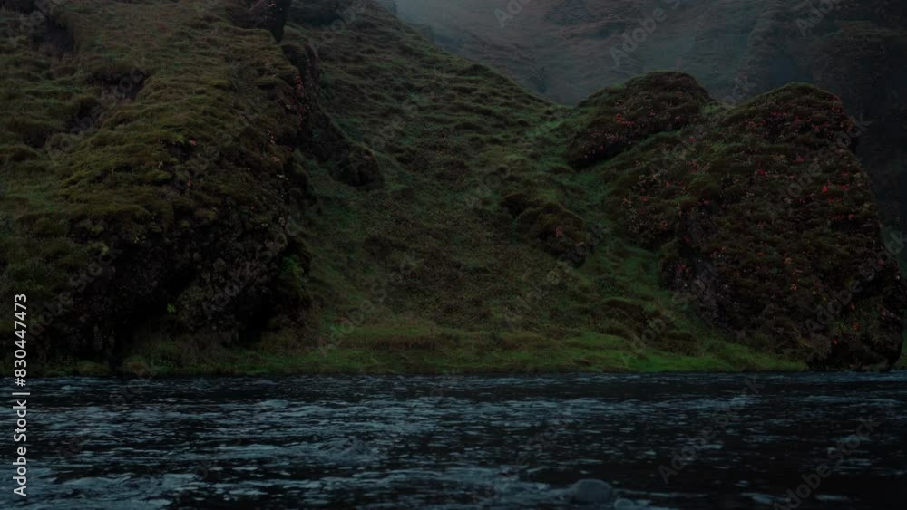 Skoga River flowing from Skogafoss waterfall in Iceland on a dark, cloudy morning. Perfect for relaxation and meditation. Skoga River flowing from Skogafoss waterfall in Iceland on a dark, cloudy morning. Perfect for relaxation and meditation.