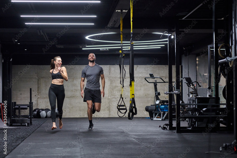 A fit couple in a modern gym, engaging in running exercises and showcasing their athletic prowess with a dynamic start. A fit couple in a modern gym, engaging in running exercises and showcasing their athletic prowess with a dynamic start.