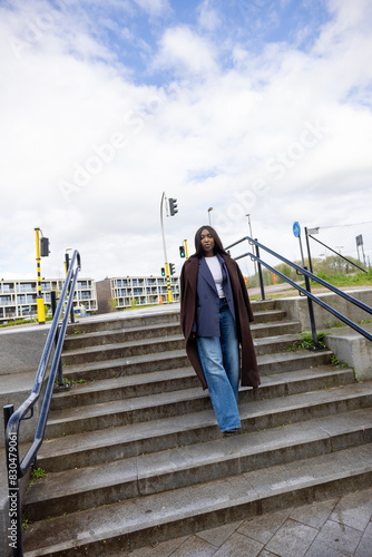 Observing a fashionable individual in a long coat and flared jeans descending stairs in an urban setting photo