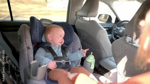 A mother prepares to unbuckle her baby from a car seat, ensuring the child's safety and comfort during the transition. photo