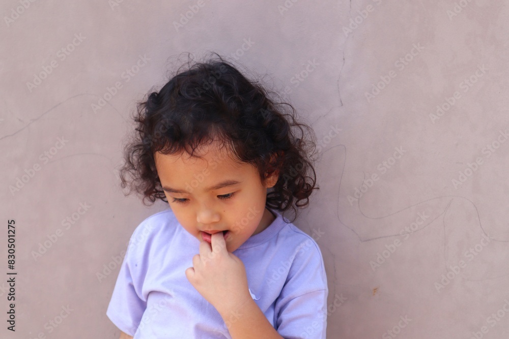 Portrait of a toddler girl standing while biting her finger. Portrait of a toddler girl standing while biting her finger.