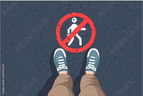 man legs in sneakers standing on asphalt road and No walking sign
