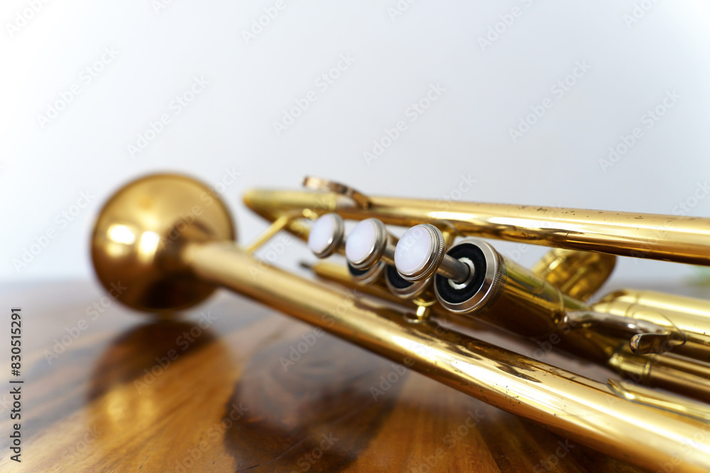Obraz premium close-up of an old trumpet on a wooden table with a white wall in the background