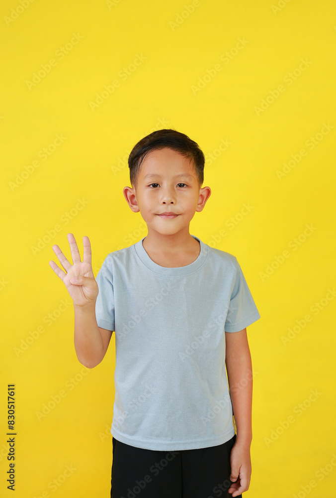 Portrait of Asian boy child show four fingers and looking straight while standing isolated on yellow background. Portrait of Asian boy child show four fingers and looking straight while standing isolated on yellow background.