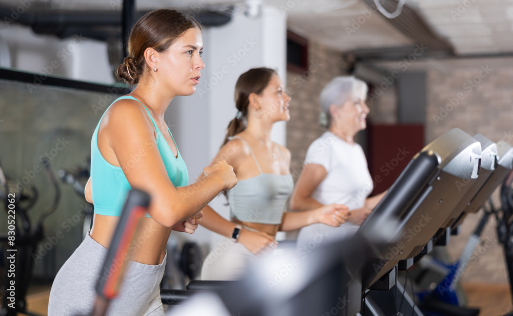 Fototapeta premium Young woman in sportswear training on treadmill in gym