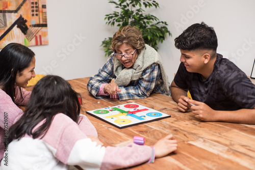 Different generations playing ludo board game at home