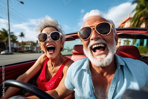 Happy senior couple taking selfie on new convertible car - Mature people having fun together during road trip vacation - Elderly lifestyle and travel transportation concept.