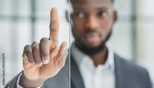 A black man in business suit pointing directly at the camera or screen, interacting or selecting on the touchscreen technology diversity presentation meeting.